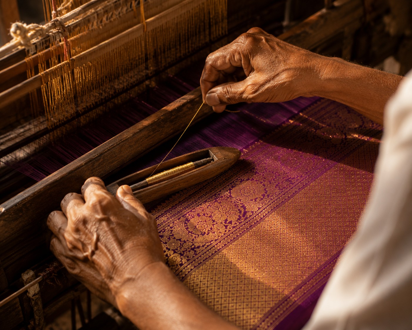 Purple silk and gold thread held in place on a traditional loom